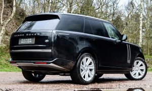 Schwarzer SUV auf schlammigem Waldweg mit Pf&uuml;tzen &ndash; SUV-Aufnahme im Gel&auml;nde bei bew&ouml;lktem Wetter