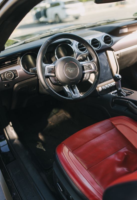 Innenraum eines Ford Mustang mit rotem Ledersitz und gepflegtem Cockpit &ndash; Fokus auf Fahrzeugaufbereitung