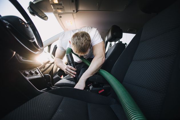 Fahrzeuginnenreinigung mit Staubsauger &ndash; Autopfleger saugt gr&uuml;ndlich den Innenraum bei der professionellen Aufbereitung